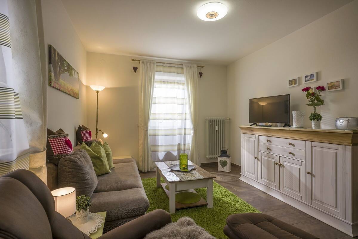 Een gezellige woonkamer met een zithoek, een salontafel en een televisie op een kast.