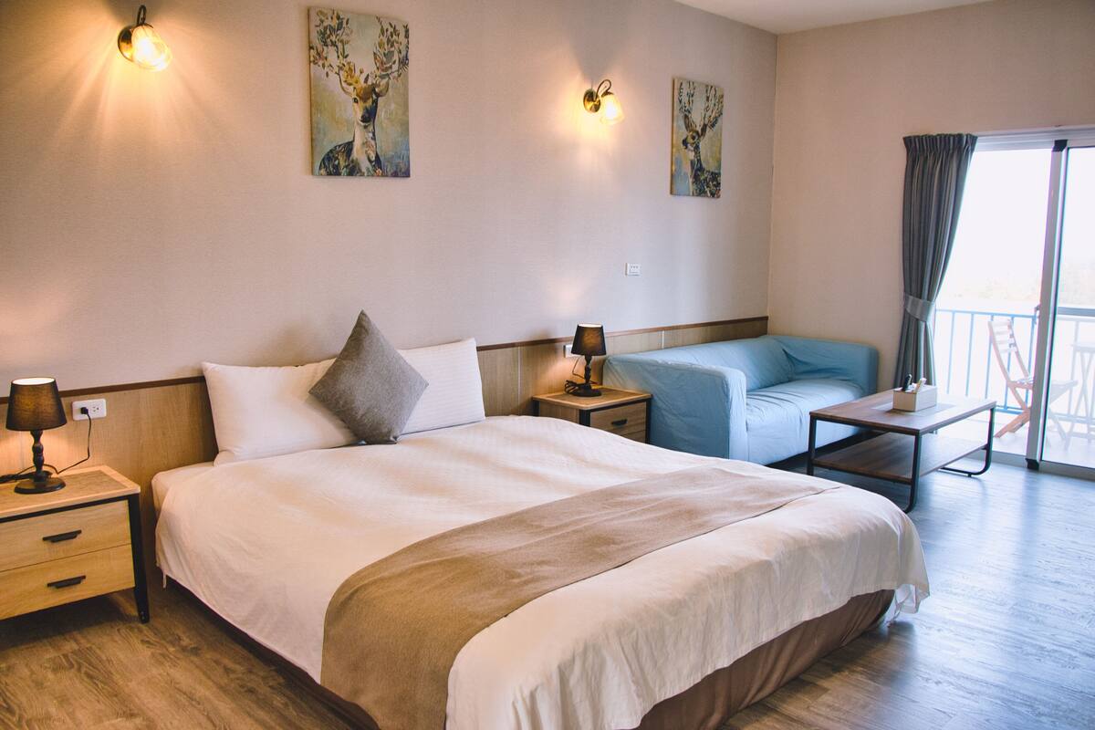 Una habitación de hotel con una cama grande, un sofá pequeño y un balcón con vistas.