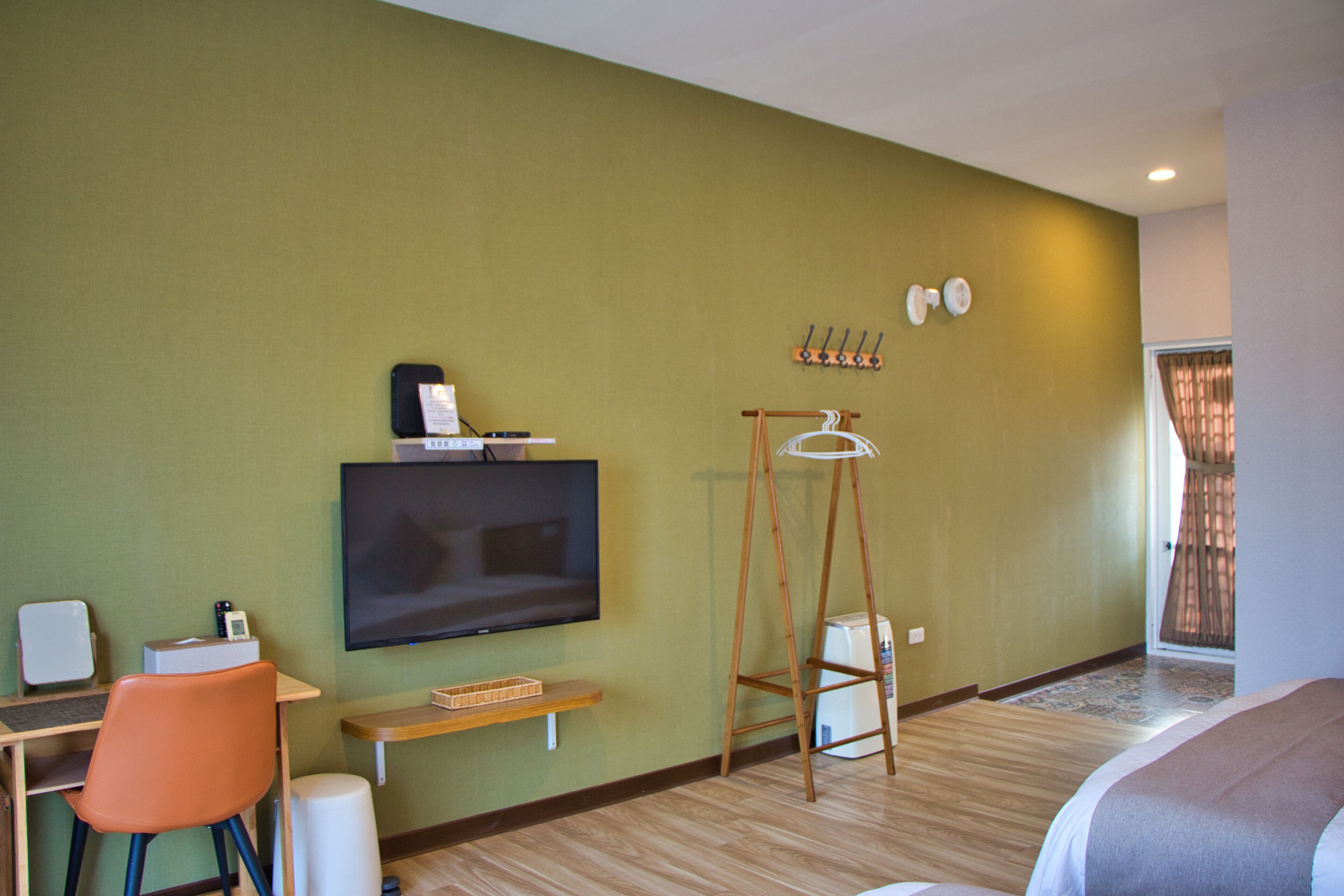 A hotel room with a bed, a desk with a computer, a television, and a chair.