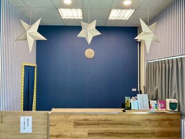 Un mostrador de recepción con un reloj, adornos con forma de estrella y una pared azul.