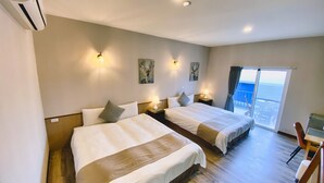 Habitación de hotel con dos camas, un balcón y vistas, además de un área de comedor.