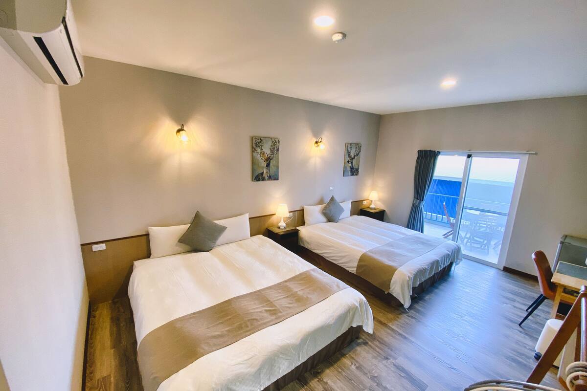 Habitación de hotel con dos camas, un balcón y vistas, además de un área de comedor.