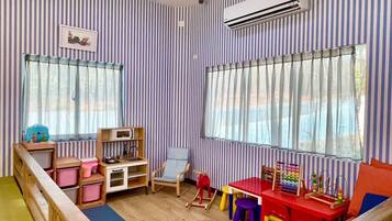 A children's playroom with striped walls, a wooden bench, a rocking chair, and a red table with toys.