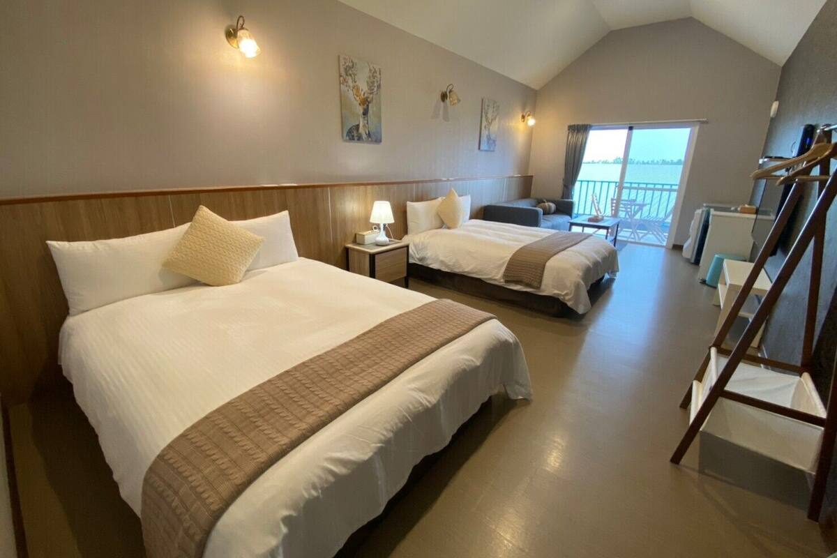 Habitación de hotel con dos camas, balcón y vista al mar.