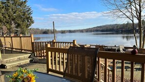 Une terrasse en bois avec une table et des chaises donnant sur un lac paisible.