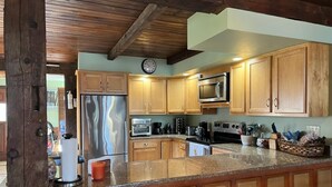 Une cuisine dotée de meubles en bois, d’appareils électroménagers en acier inoxydable et d’un plan de travail en granit.