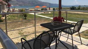 Ein Balkon mit Tisch und Stühlen mit Blick auf Strand und Berge.