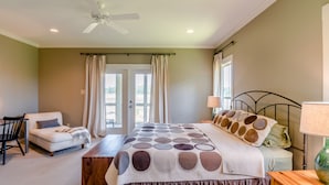 A bedroom with a bed, a chair, a desk, and a window with curtains.