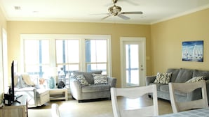 A spacious living room with a ceiling fan, two sofas, a coffee table, and a dining table.