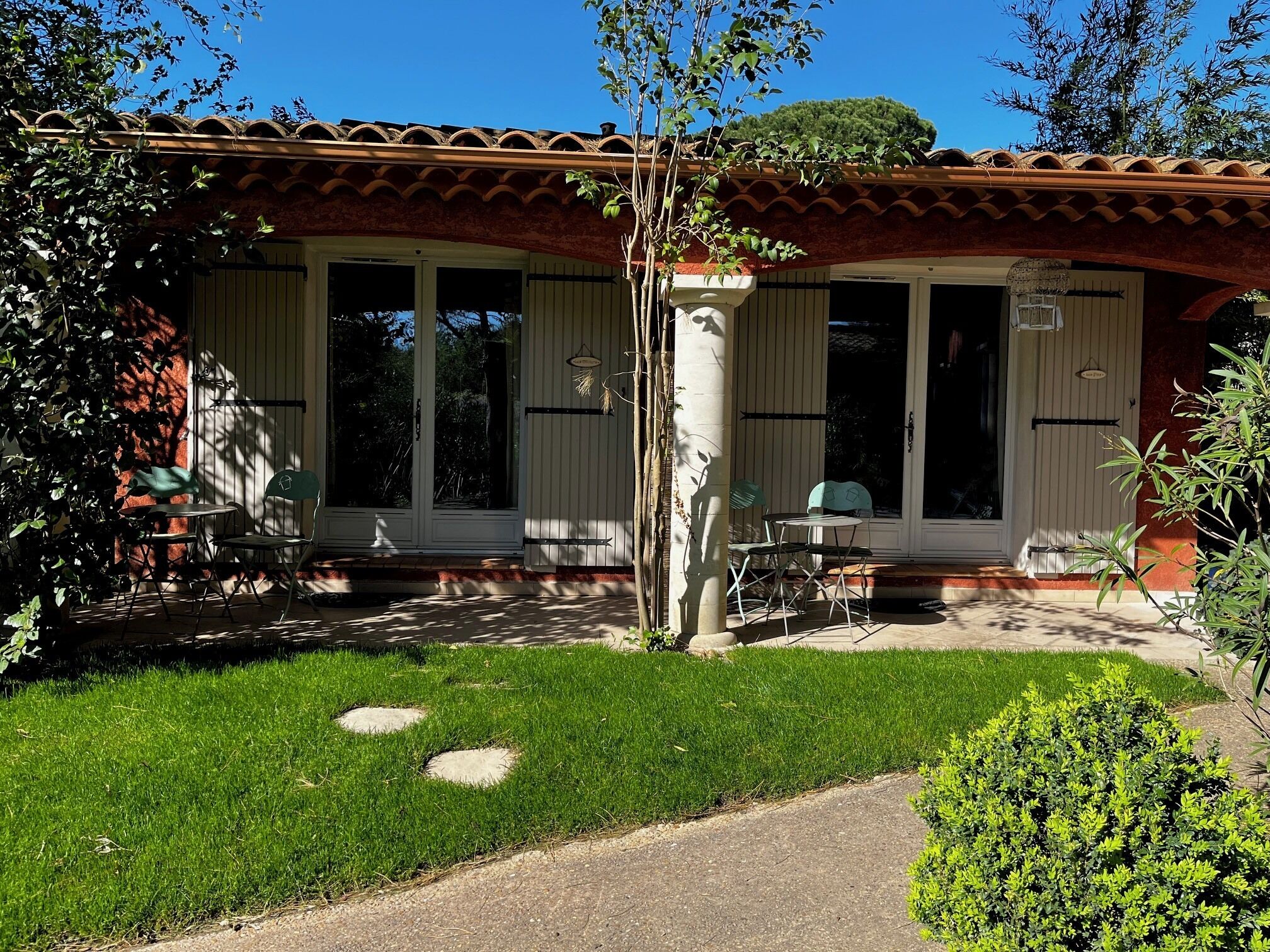 Una casa con tetto in tegole, un portico coperto con sedie e un prato curato.