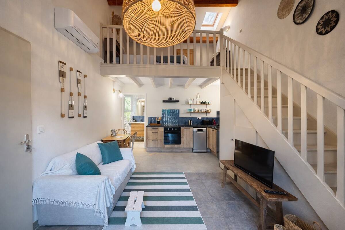 A spacious living area with a sofa, a dining table, a kitchen, and a staircase.