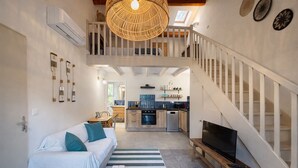 A spacious living area with a sofa, a dining table, a kitchen, and a staircase. - La Bastide Des Pins (Castillon-du-Gard)