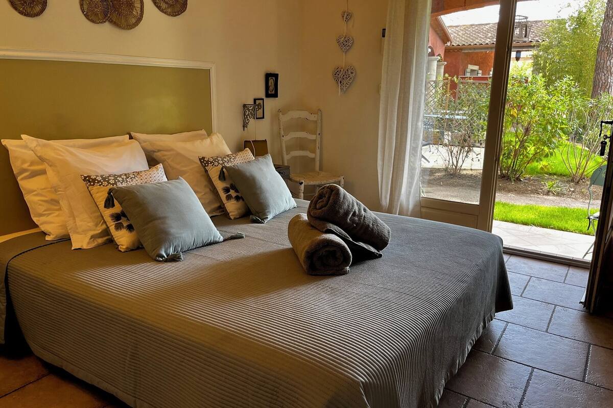 A bed with a striped bedspread, multiple pillows, and a rolled towel.