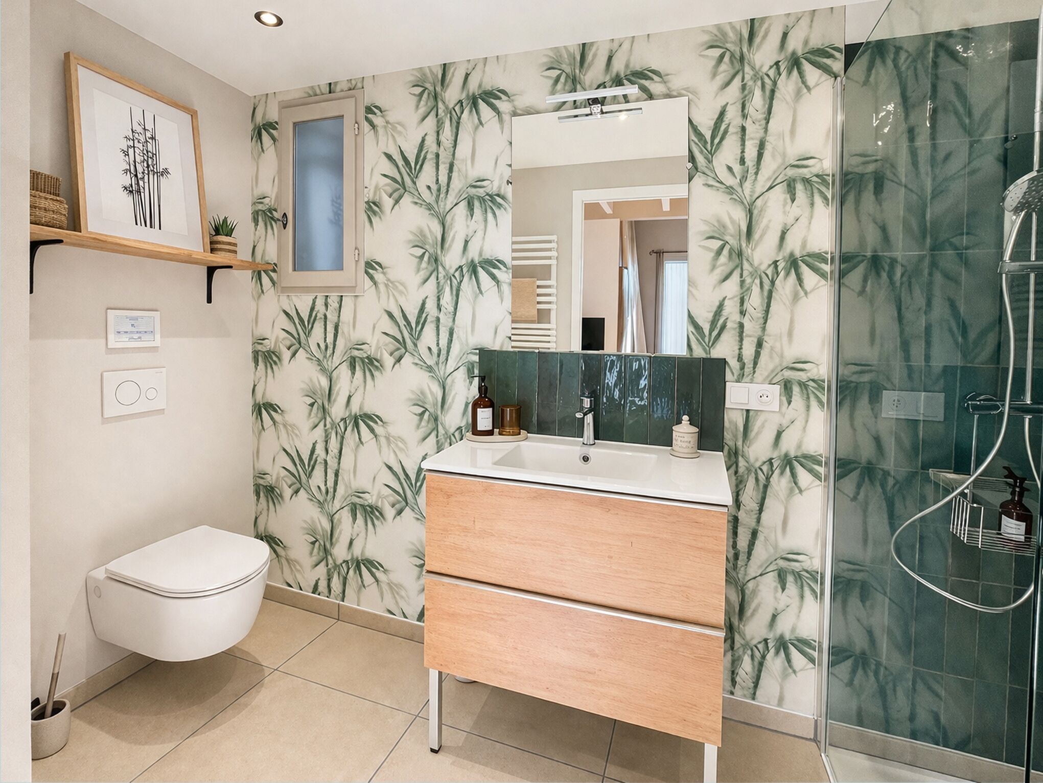 A bathroom with a toilet, a sink with a mirror, a shower, and bamboo-themed wallpaper.
