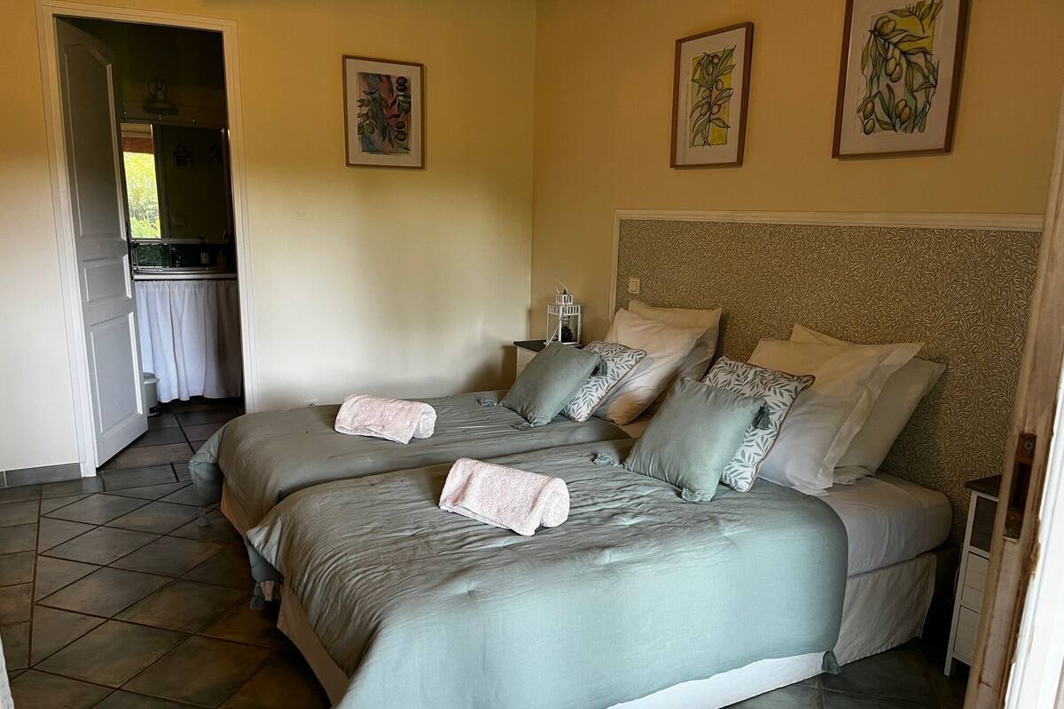 A bedroom with two beds, a headboard, and artwork on the walls.