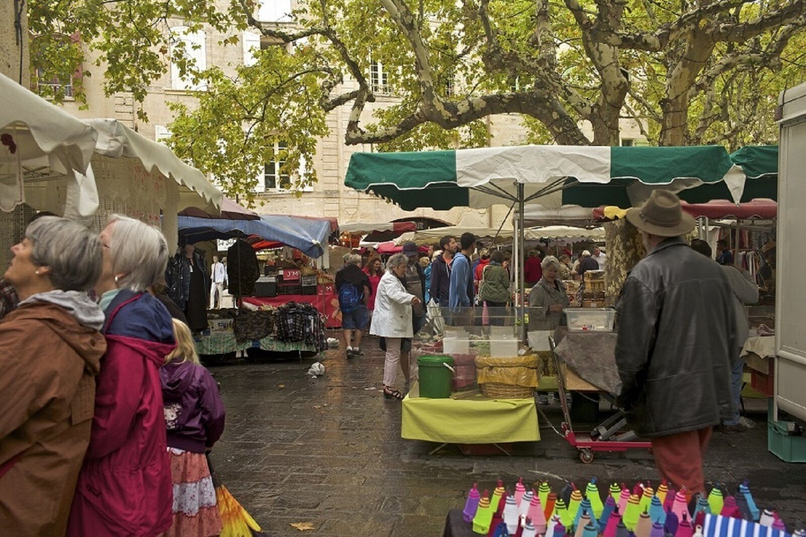 Een levendige markt met verschillende kraampjes en mensen die aan het winkelen zijn.