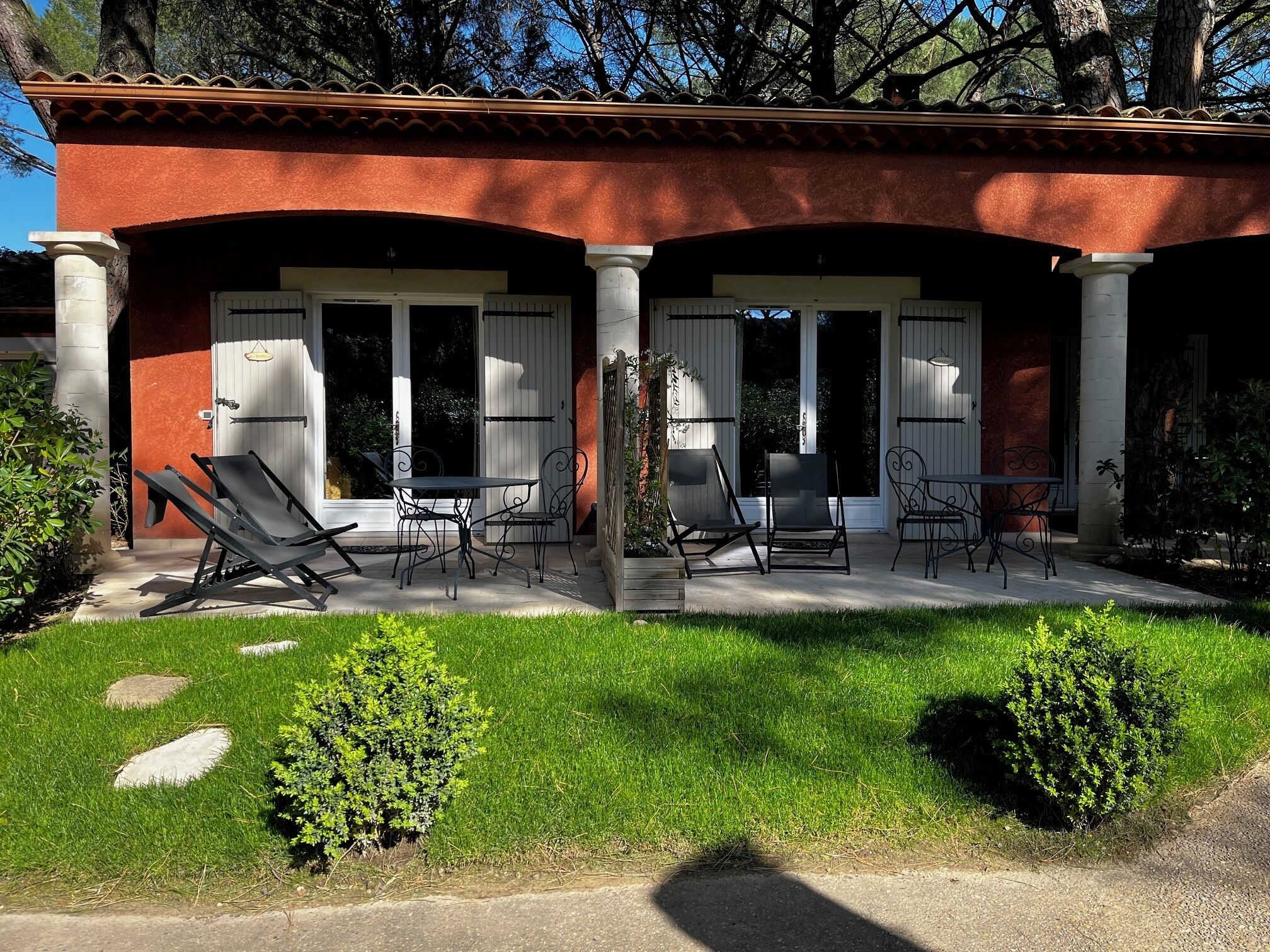 Una casa de dos pisos con un porche cubierto, mobiliario exterior y un césped bien cuidado.