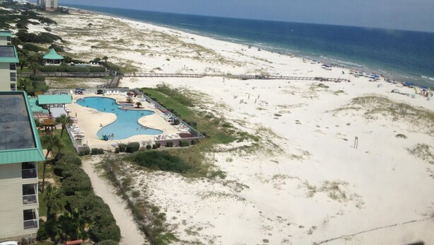 A beach resort with a large pool area, a boardwalk, and a view of the ocean.