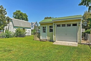 Une maison de plain-pied avec un garage, un petit abri de jardin et une pelouse bien entretenue.