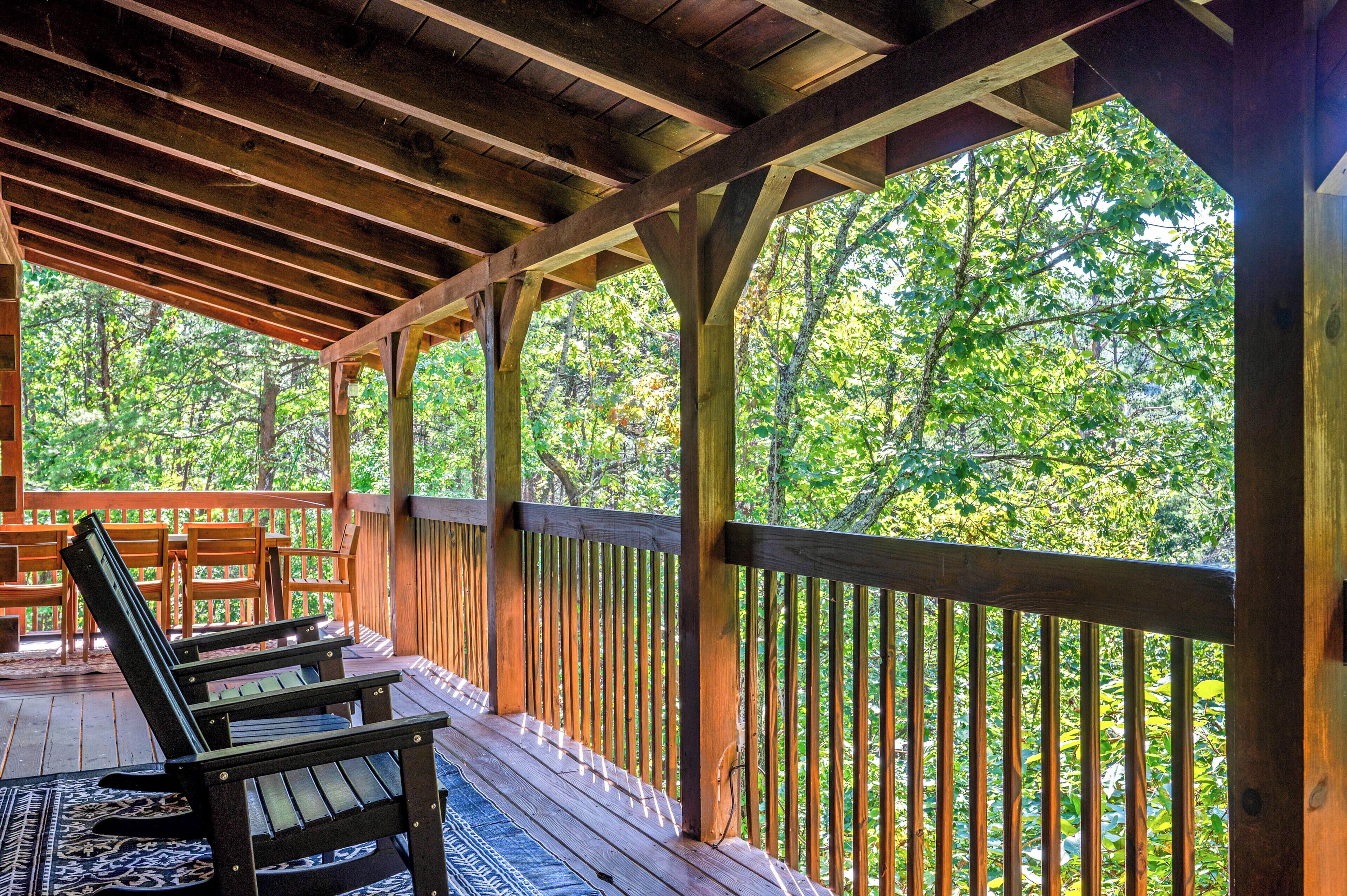 Une terrasse en bois, dotée de bancs et d’une rambarde, qui offre une vue sur une zone boisée.