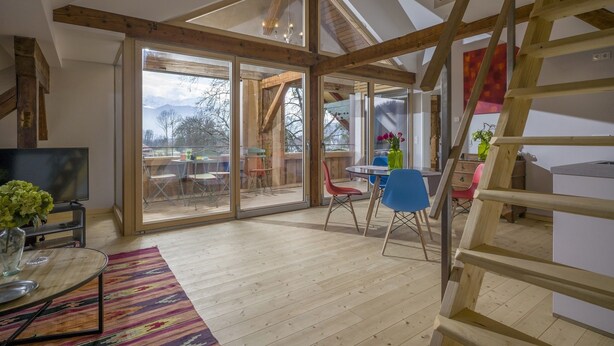 Un loft espacioso con techo alto, ventanas amplias y escalera de madera.