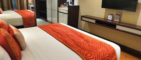 Habitación de hotel con dos camas, televisión, minibar y baño a la vista.