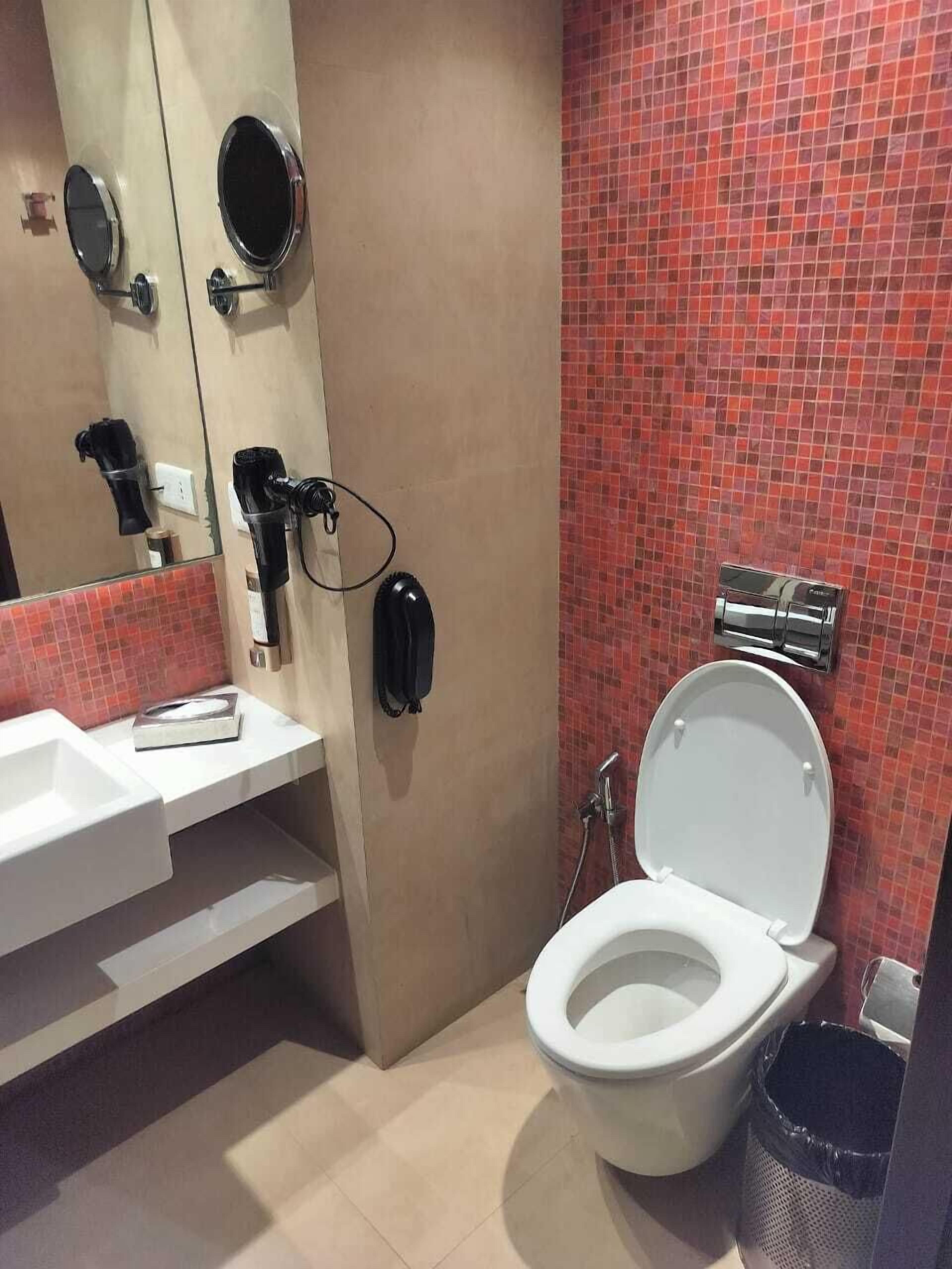 Kylpyhuone, jossa on valkoinen pesuallas, peili, wc ja suihkutila.