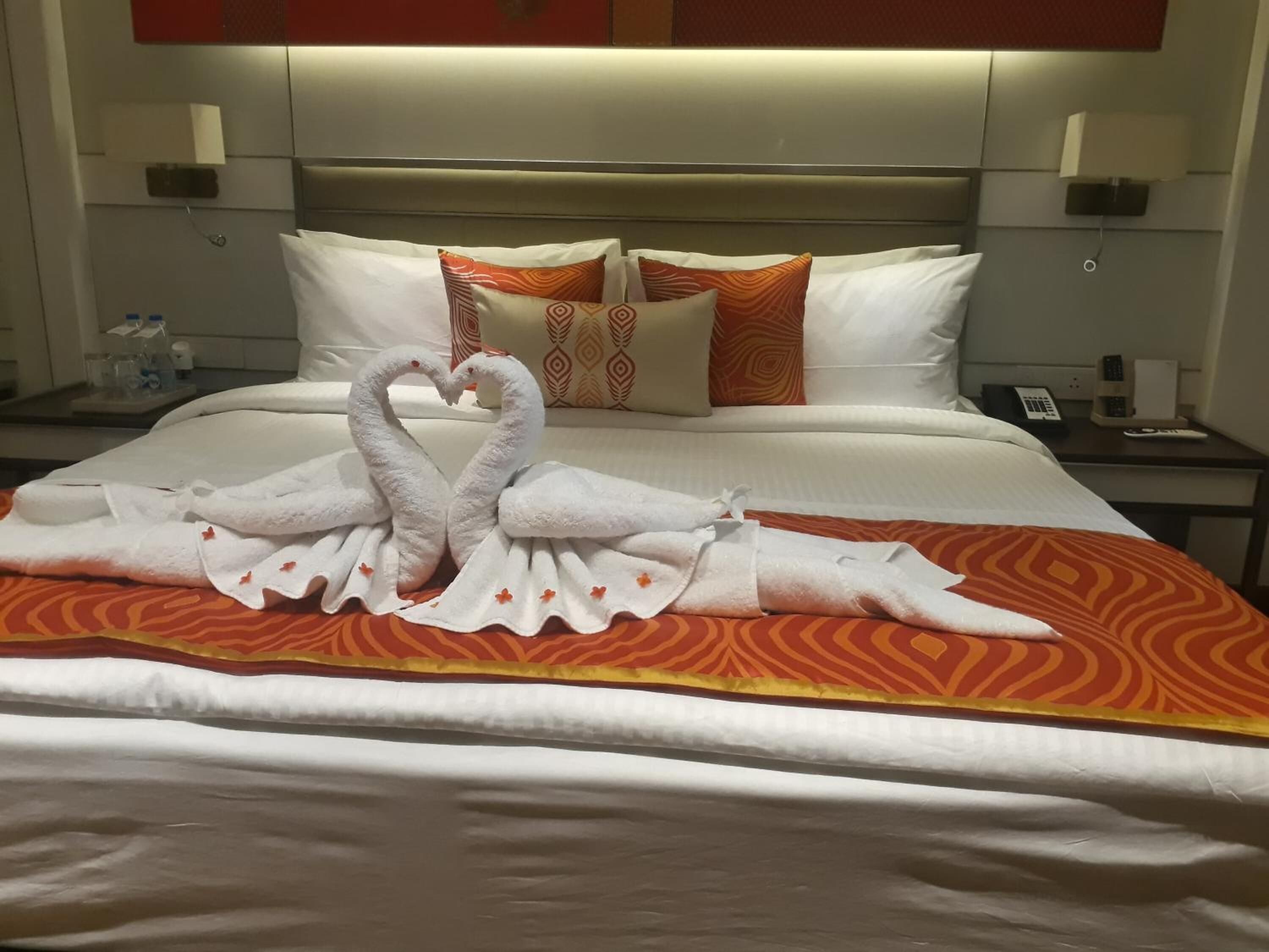A hotel room with a bed featuring a decorative towel arrangement in the shape of swans.