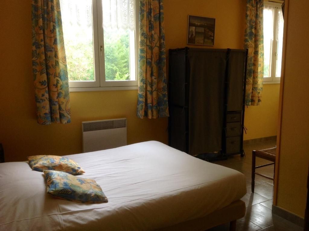 Un dormitorio con cama, cortinas, radiador, armario y una silla.