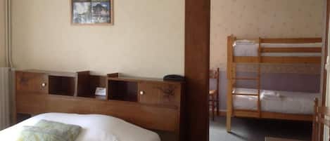 Una habitación con una cama individual, un escritorio de madera y una cama litera.