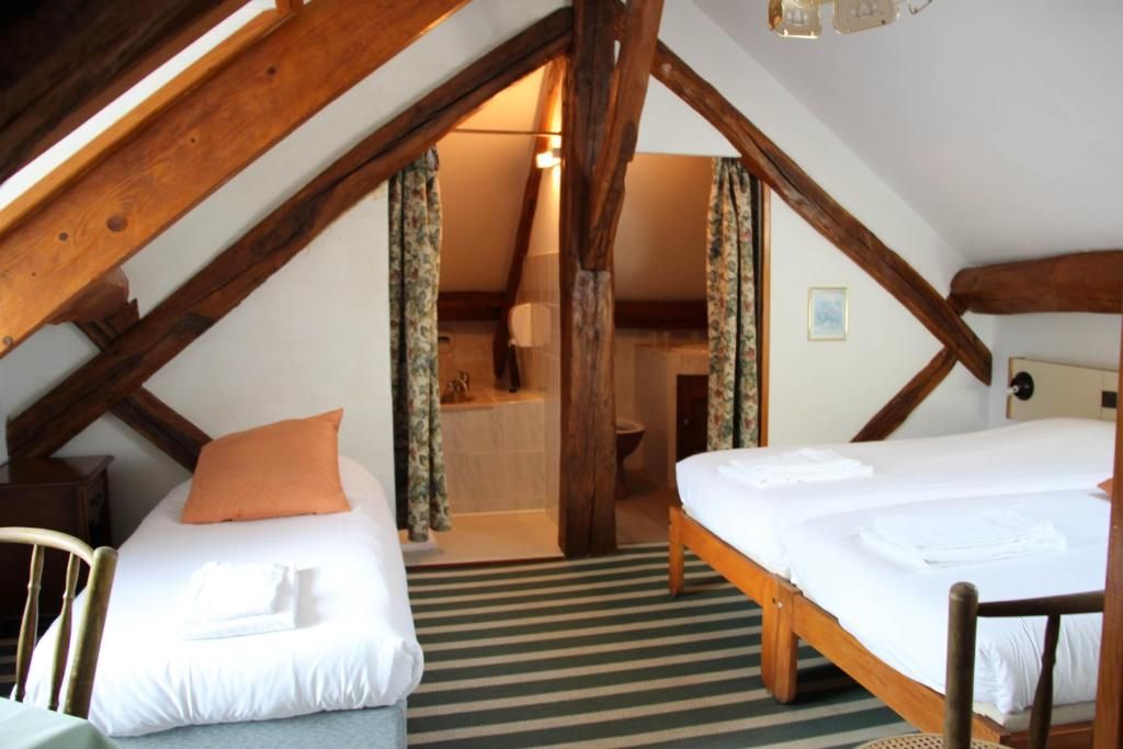 Un dormitorio acogedor en el ático con dos camas, vigas de madera y vistas al baño.