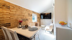 Una cocina moderna con comedor, que presenta un salpicadero de piedra, un televisor de pantalla plana y un refrigerador con fruta encima.