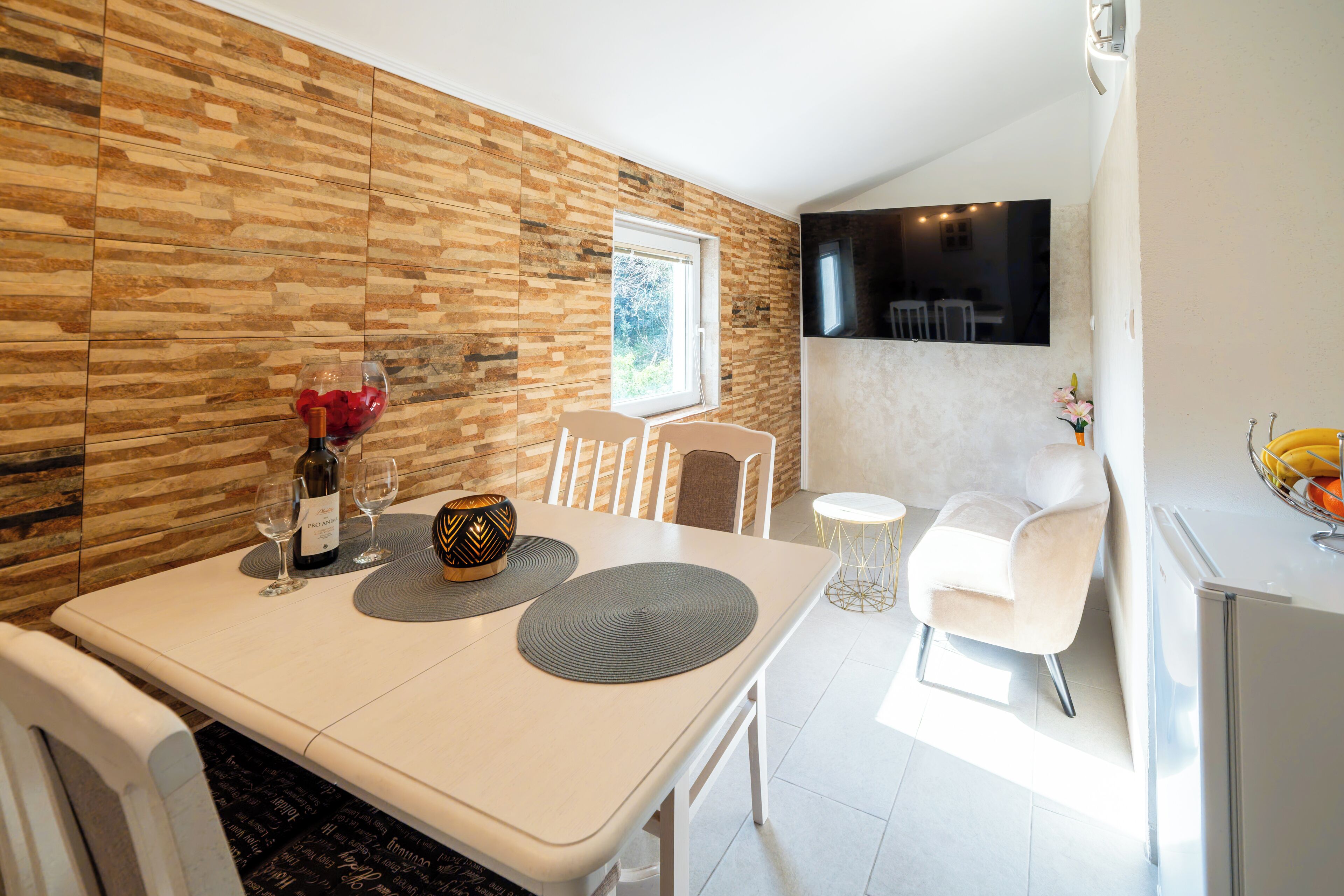 Een moderne eethoek met een witte tafel, twee stoelen, een klein rond tafeltje en een witte bank.