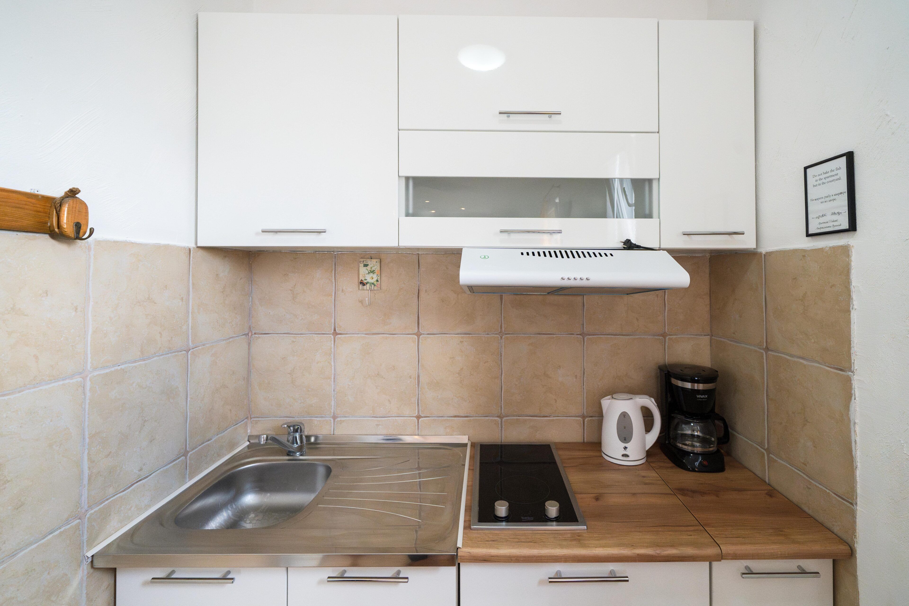 A compact kitchen with a sink, stove, and coffee maker.