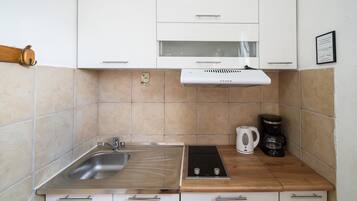 A compact kitchen with a sink, stove, and coffee maker.