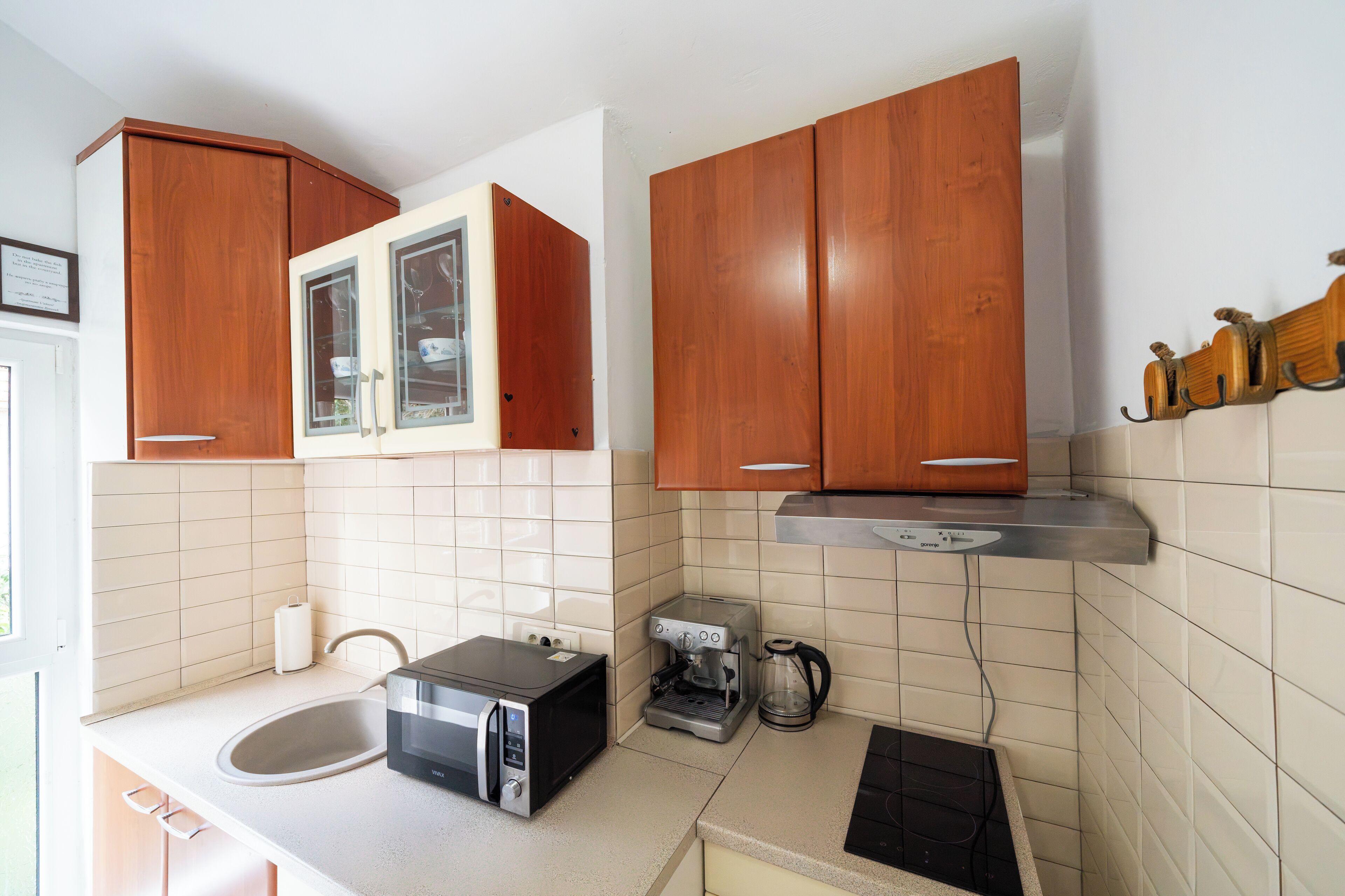 A compact kitchen with wooden cabinets, a microwave, a coffee maker, and a toaster.