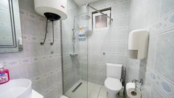 Un bagno con doccia vetro, un water e un lavandino con dispenser di sapone.