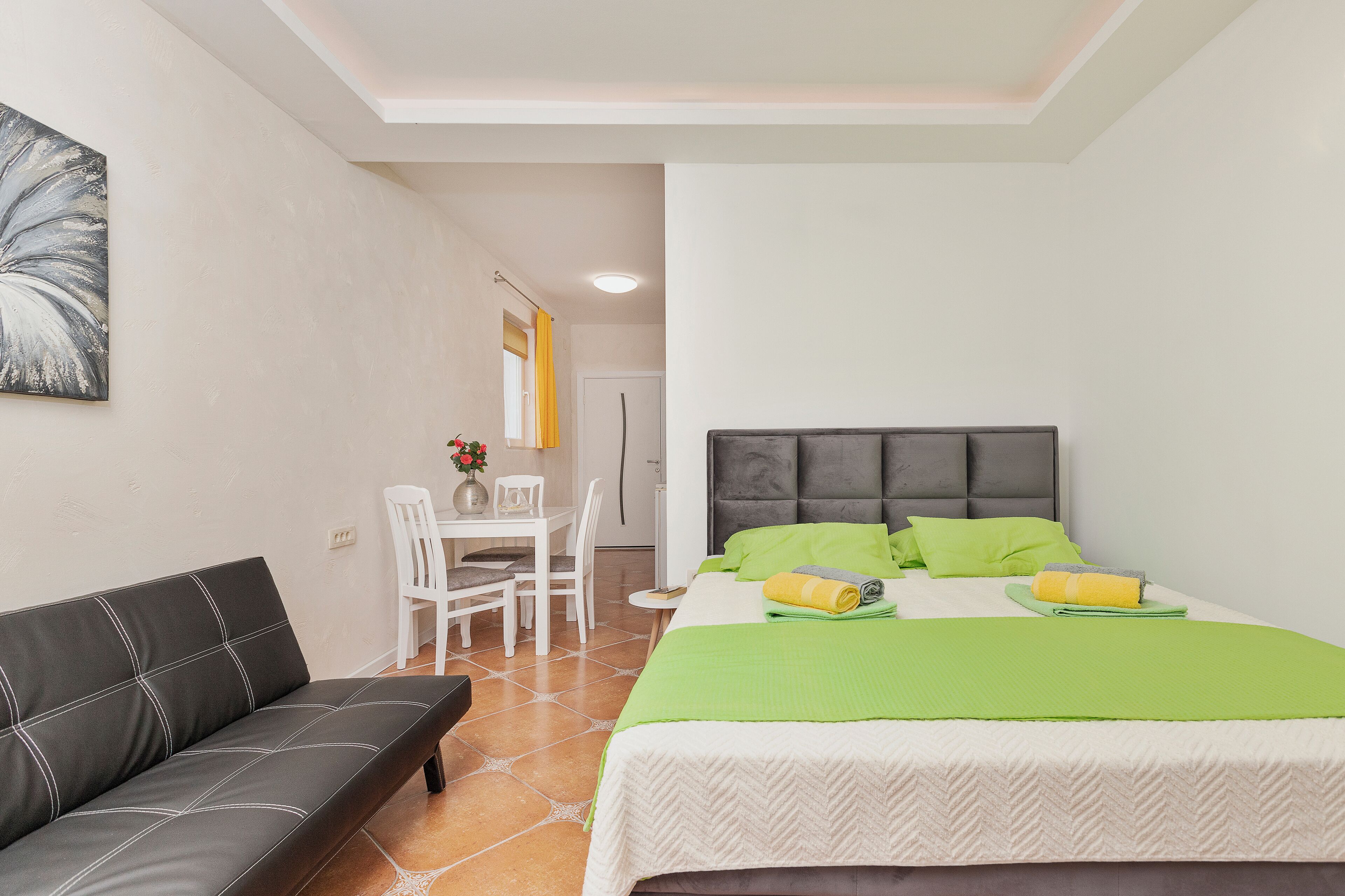 A bedroom with a bed, a sofa, a desk, and a chair.