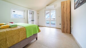 Un dormitorio con cama, ventana, balcón y puerta.