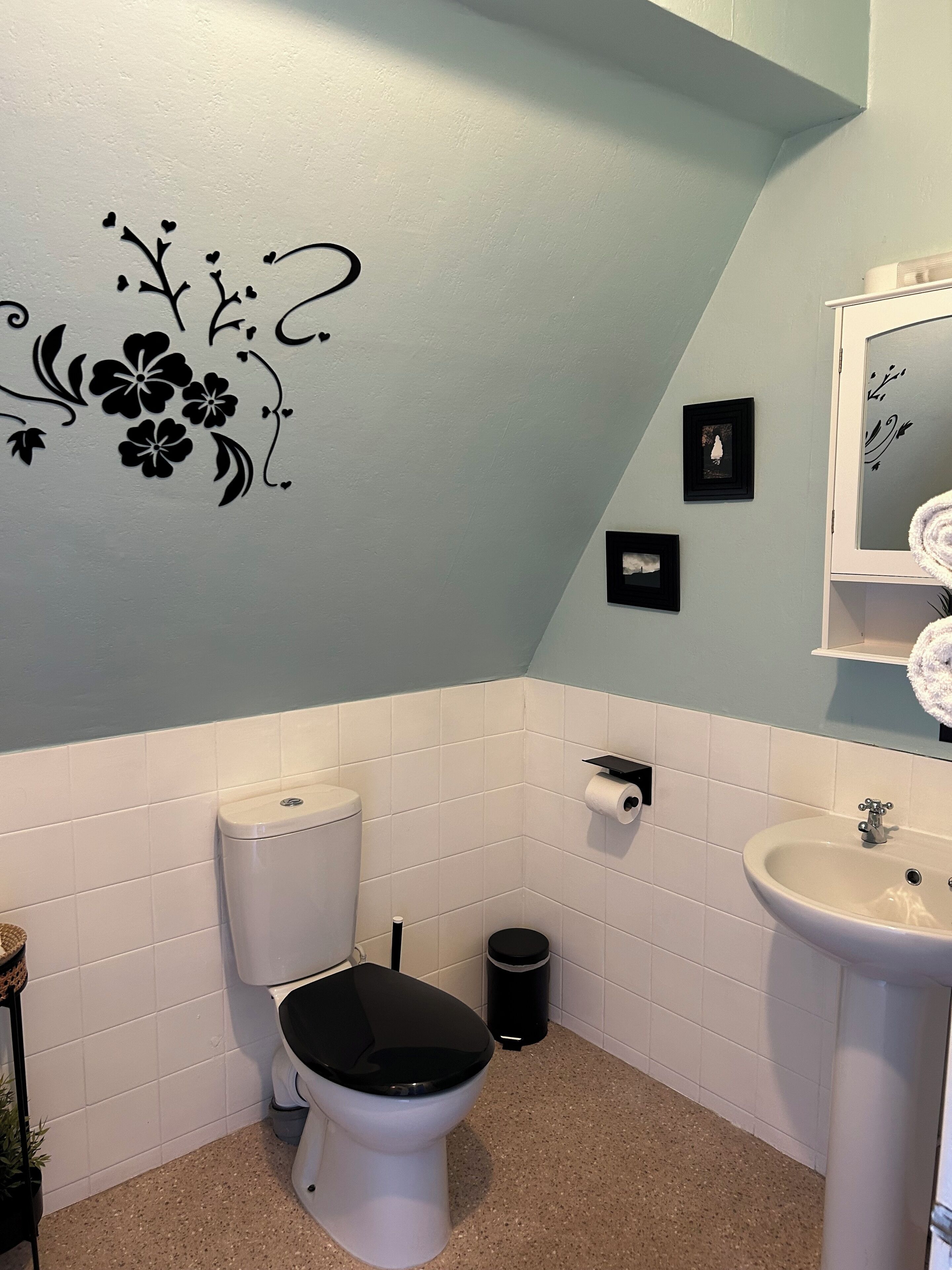 A bathroom with a toilet, sink, and decorative wall art.