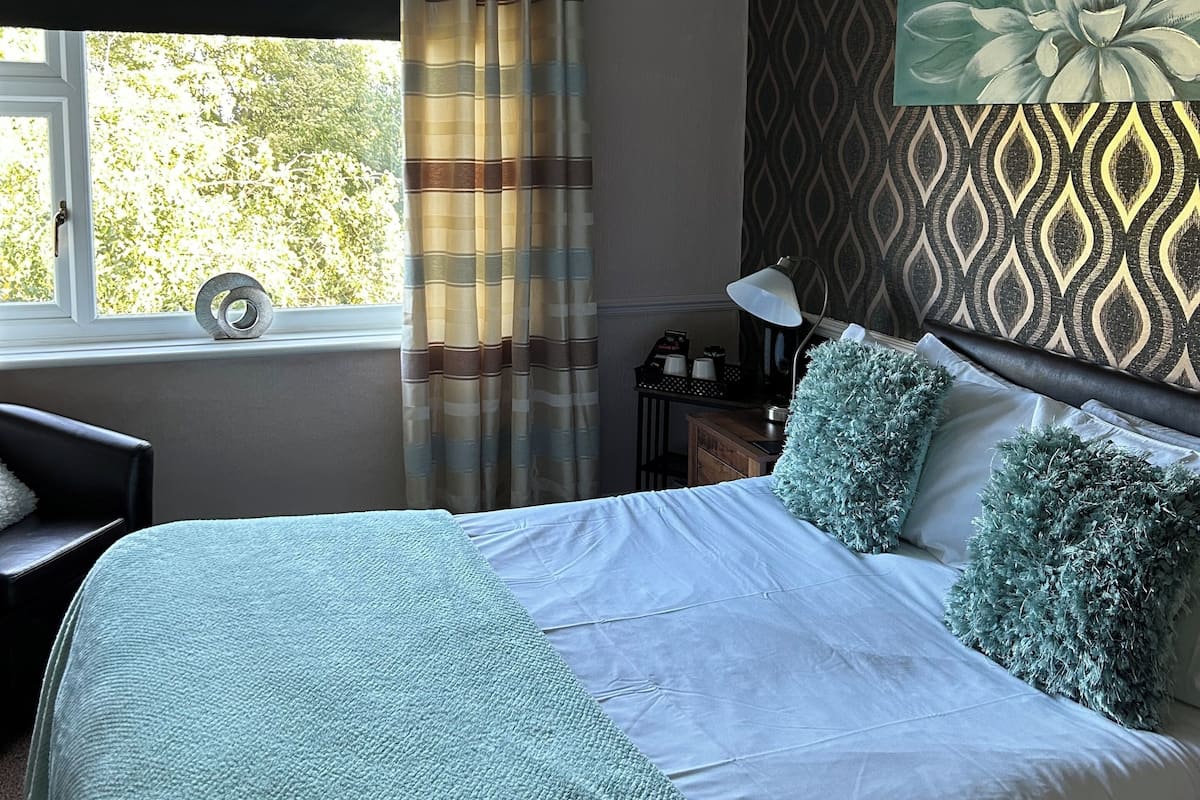 Un dormitorio ordenado con cama, escritorio y ventana con cortinas.