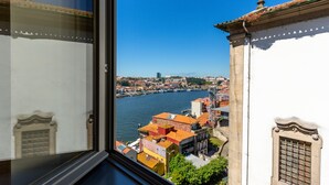 Vista da janela sobre um rio, com edifícios e uma ponte.