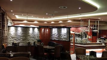 En restaurantindretning med stenvægge, træmøbler og et barområde.