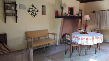 A cozy living room with a wooden bench, a round table with a floral tablecloth, and a fireplace.