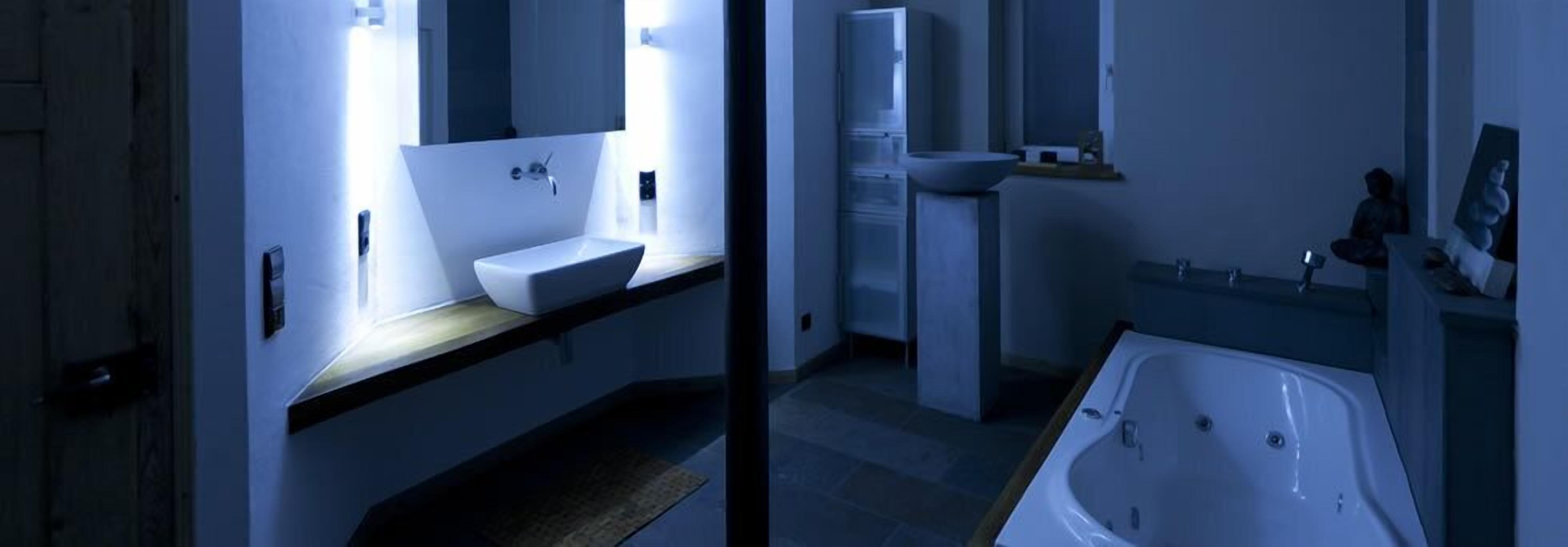 A modern bathroom with a large bathtub, a sink, and a mirror.