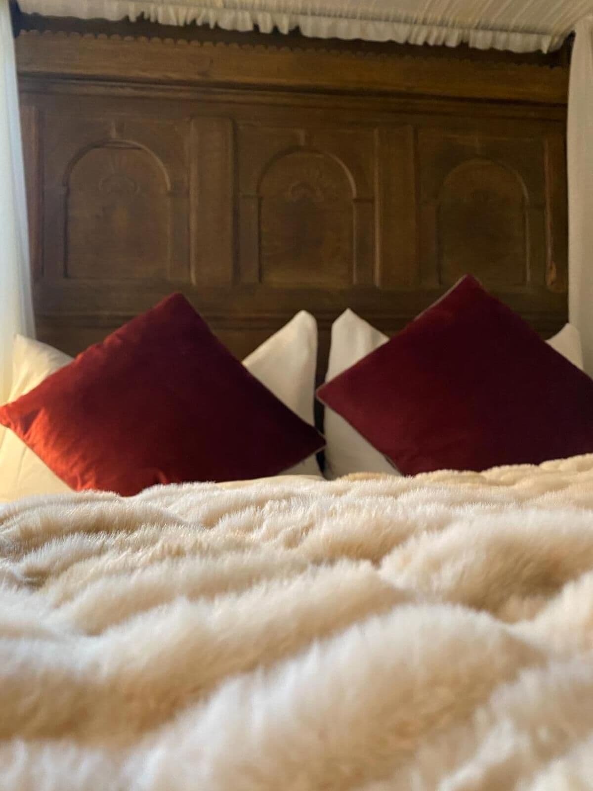 Ein Bett mit einer flauschigen weißen Daunendecke und zwei roten Kissen.