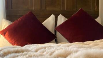 Ein Bett mit einer flauschigen weißen Daunendecke und zwei roten Kissen.