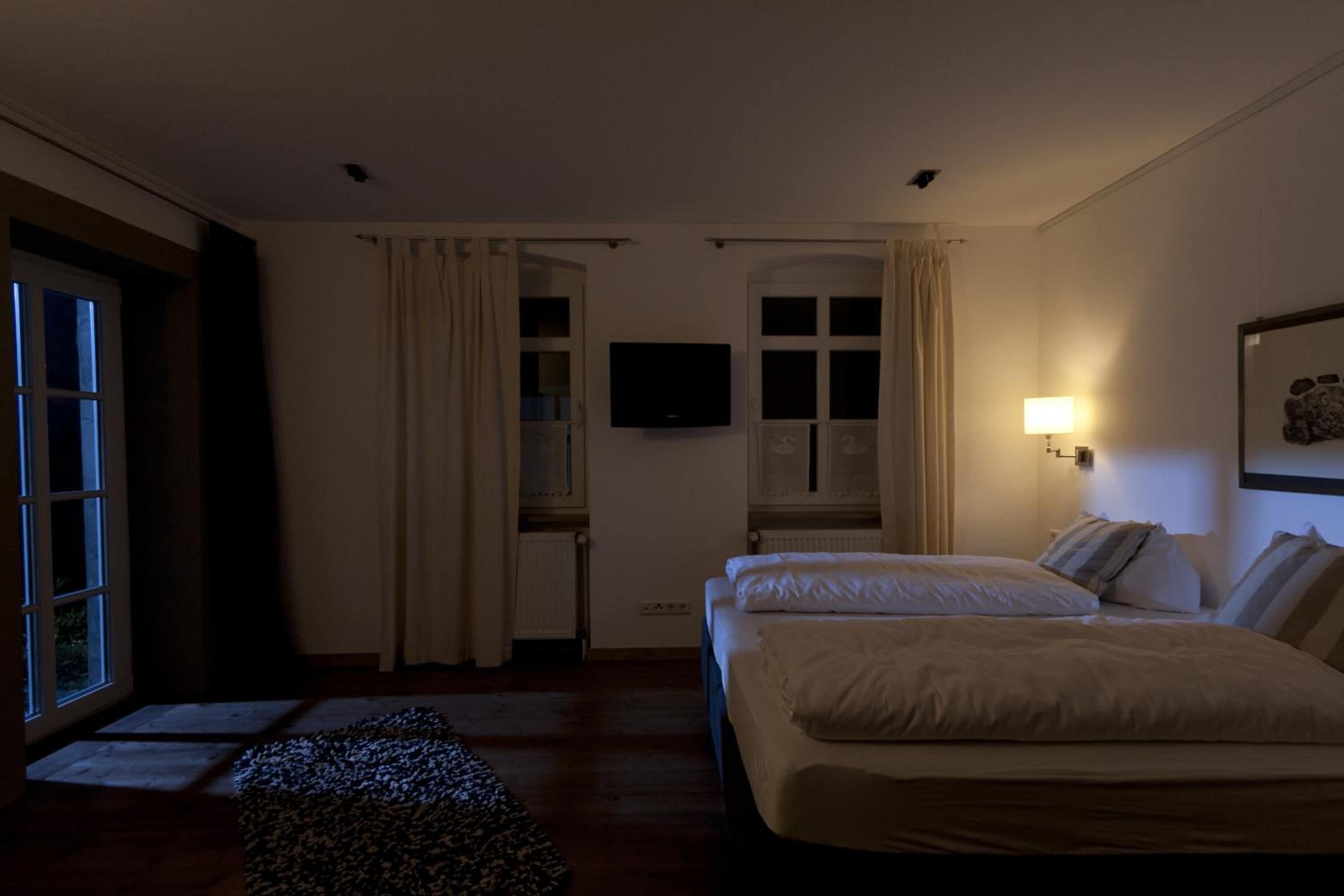 A hotel room with a bed, a television, and a window with curtains.