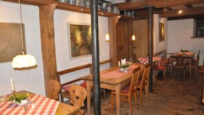 A restaurant with wooden tables and chairs, a hanging light fixture, and a painting on the wall. - Hotel Landgasthof Zum Weissen Schwanen (Braubach)