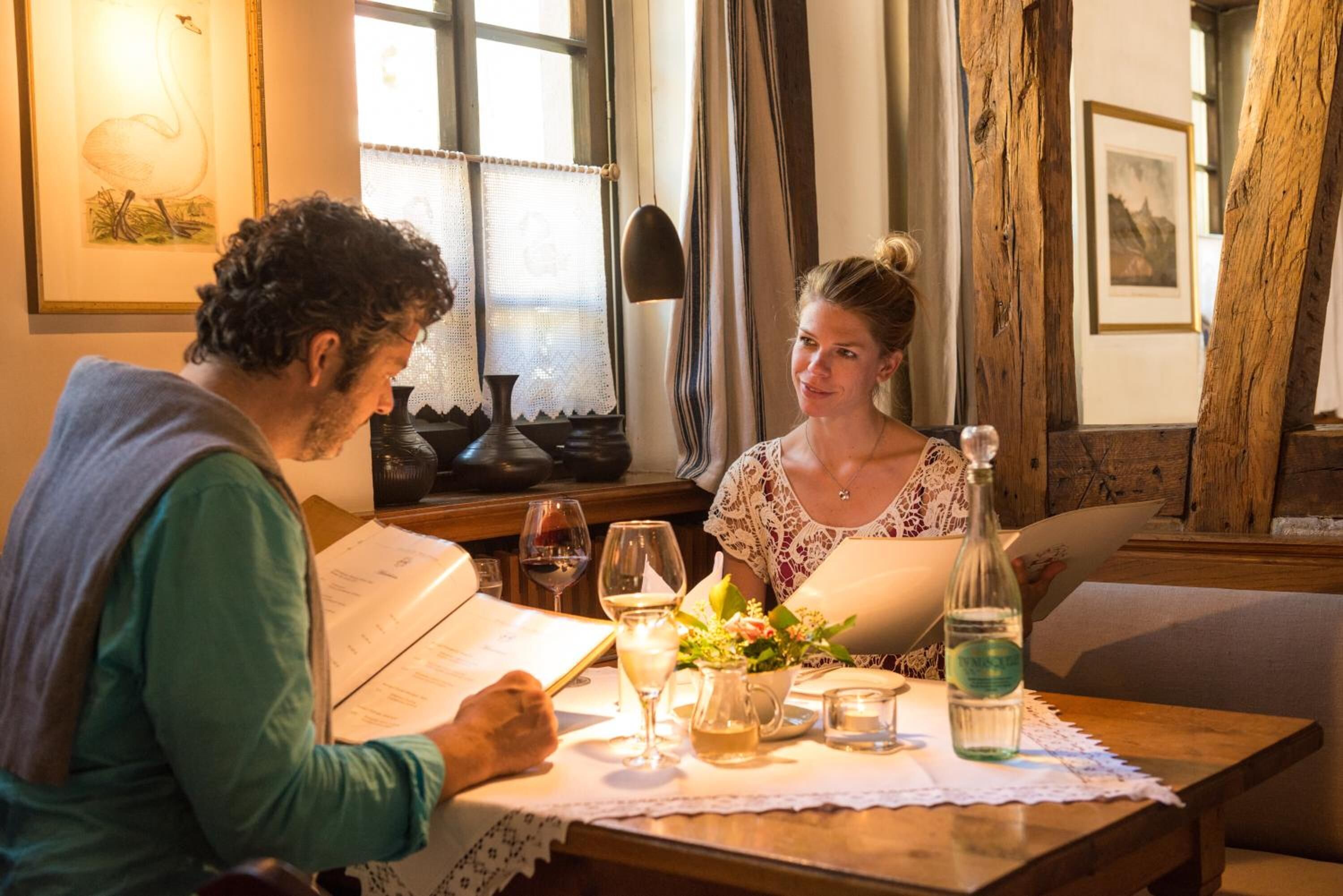 A dining table with a menu, wine glasses, and a bottle of water.
